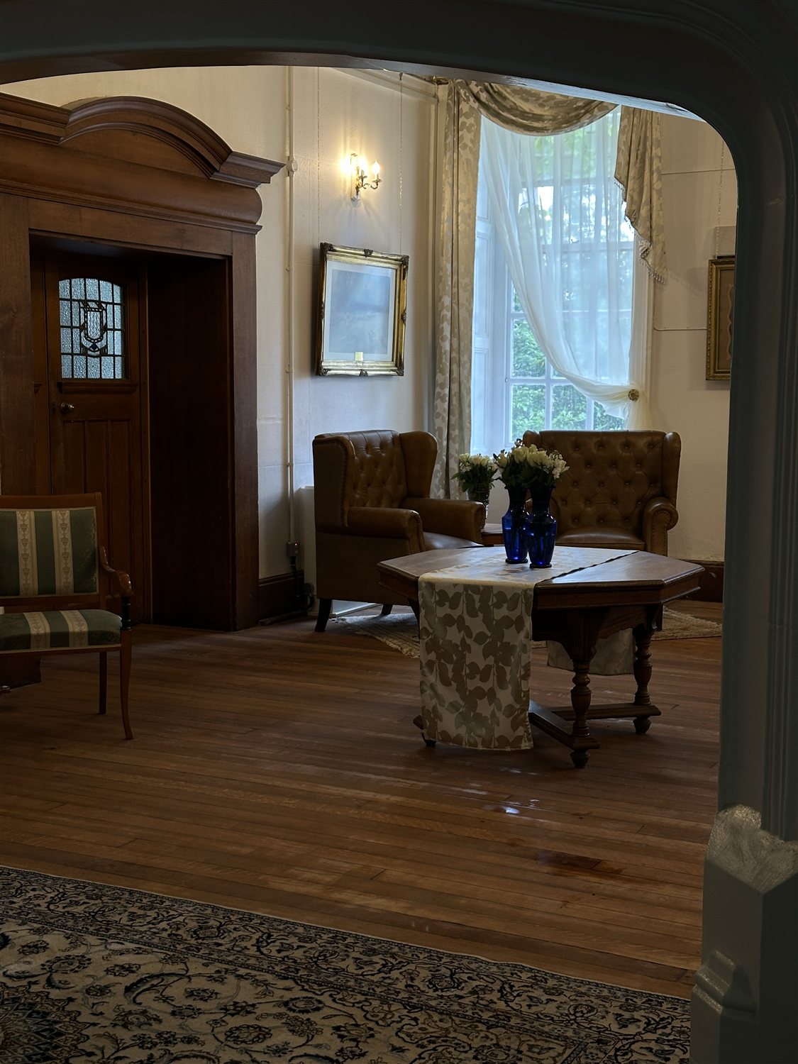 Leather armchairs and a drawn curtain seen through the stone archway
