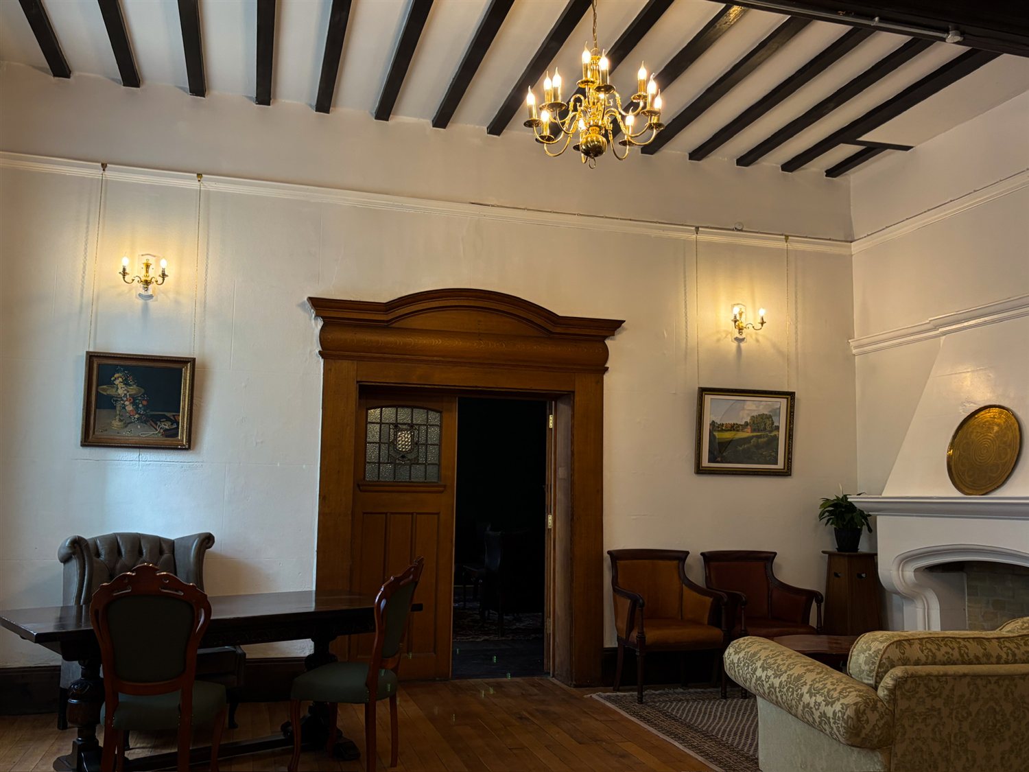 A beamed ceiling with brass chandelier, panelled doorway and period furniture