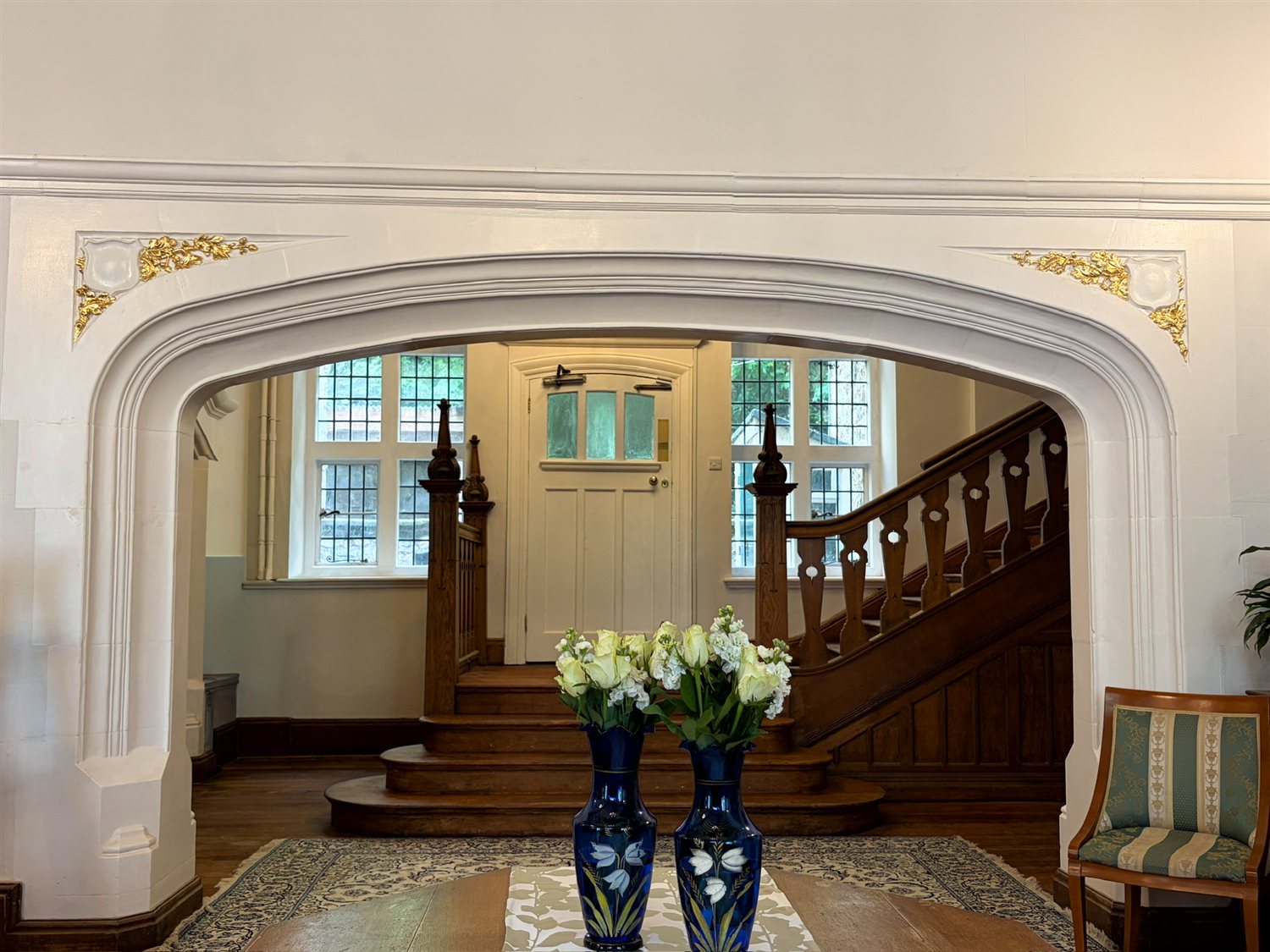 The Entrance Hall's carved stone archway with gilded details, looking towards the oak staircase
