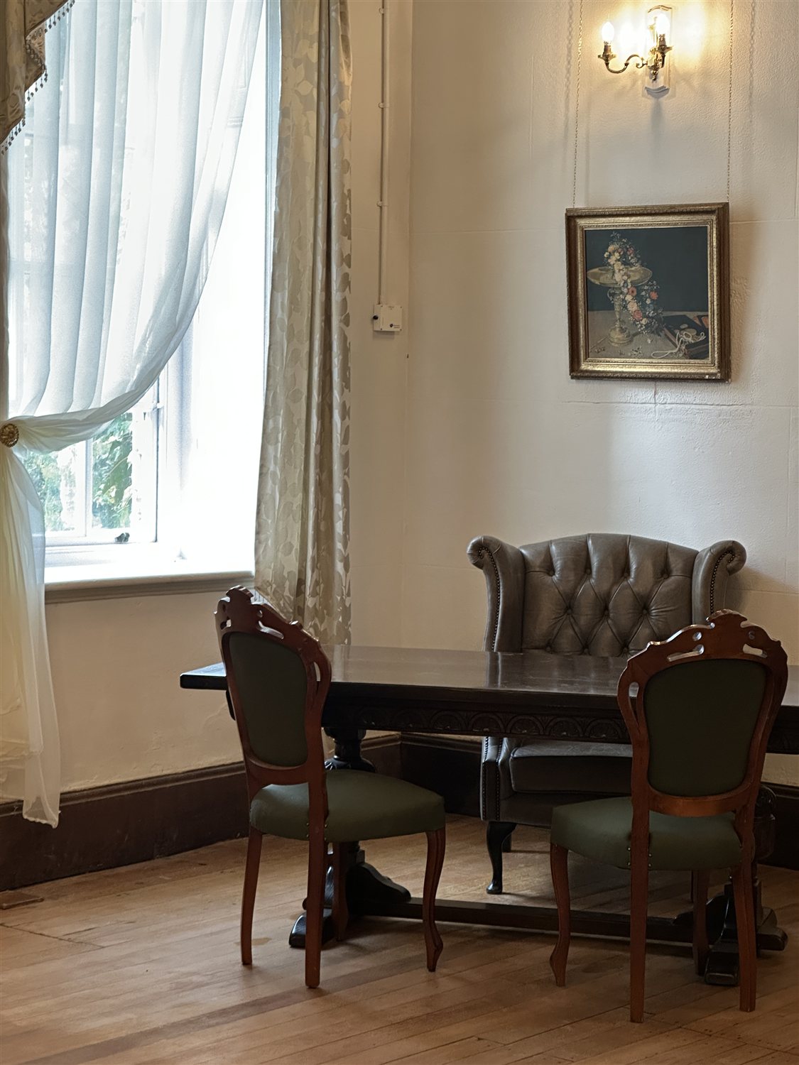 An oak table and carved chairs beside a tall window